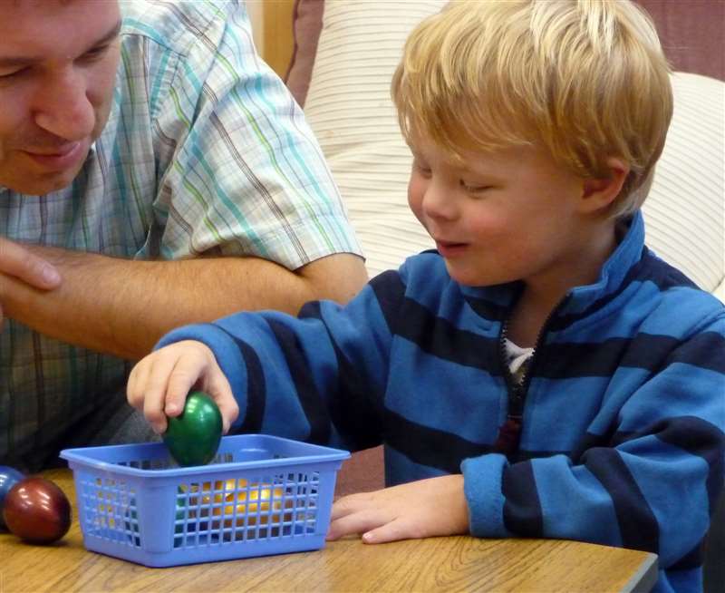 A photograph of a boy with Down syndrome counting objects