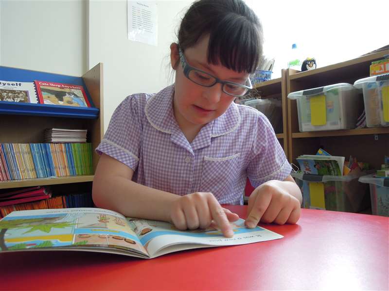 A photograph of a child with Down syndrome reading.